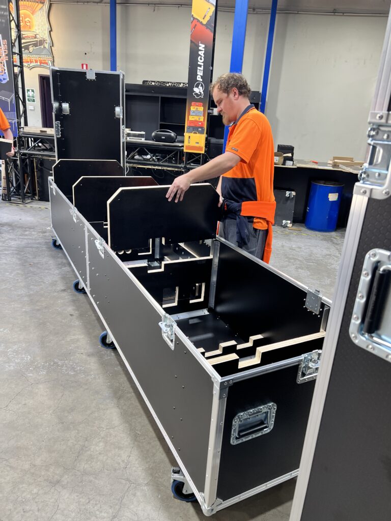 Ovation Custom team member positioning a custom plywood support inside an oversized Cirque du Soleil road case during assembly.